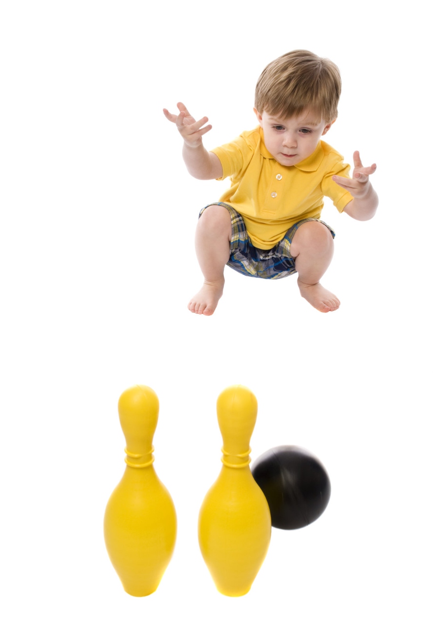 Toddler rolling a ball to knock over pins