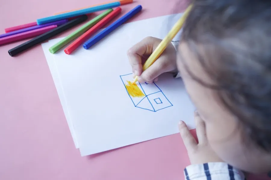 Little girl drawing a house on a piece of paper