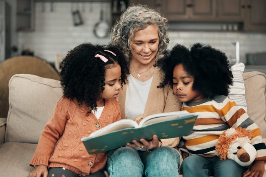 Lady reading a book to two young girls