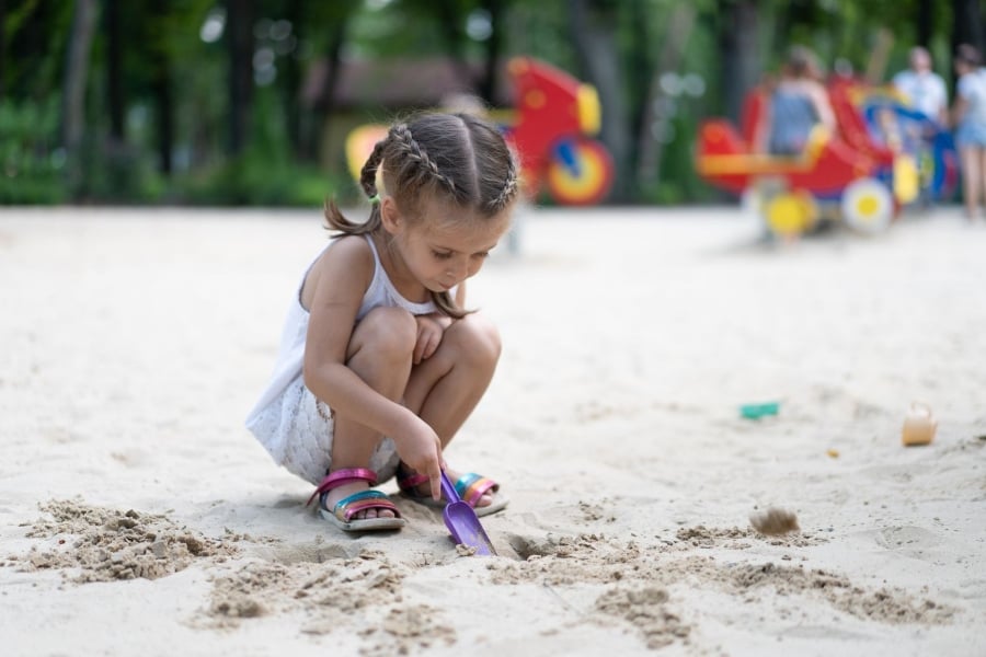 Little girl shoveling white sand