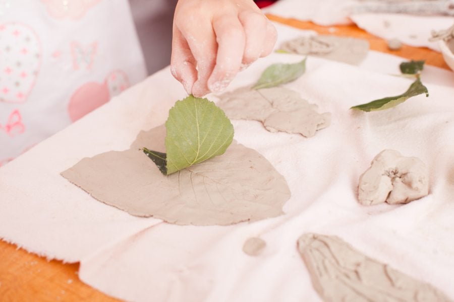 Child pressing leaves into playdough