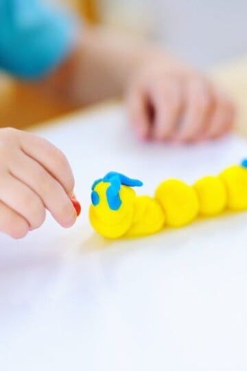 Child making a caterpillar with playdough