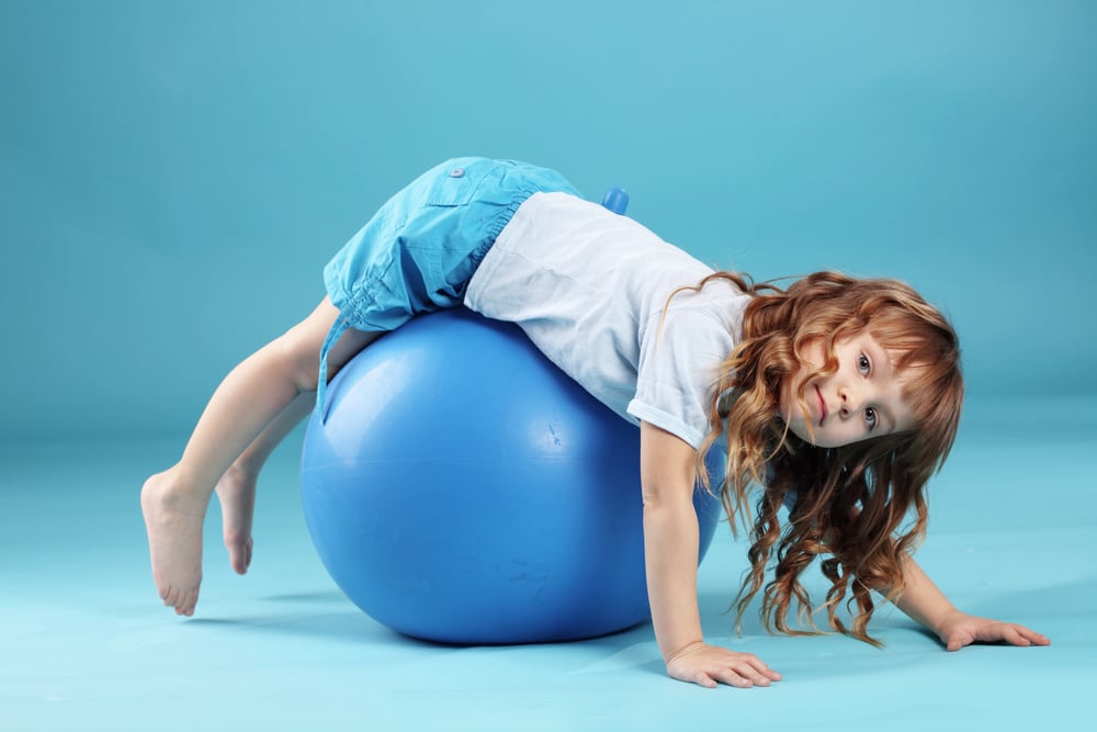 Young girl rolling on an exercise ball.