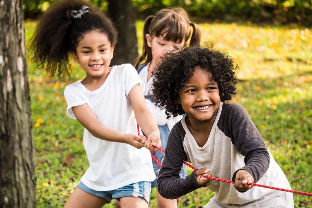 Children in a park playing tug-of-war