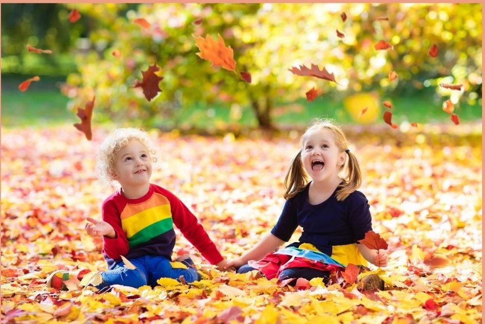 Children playing in colourful autumn leaves
